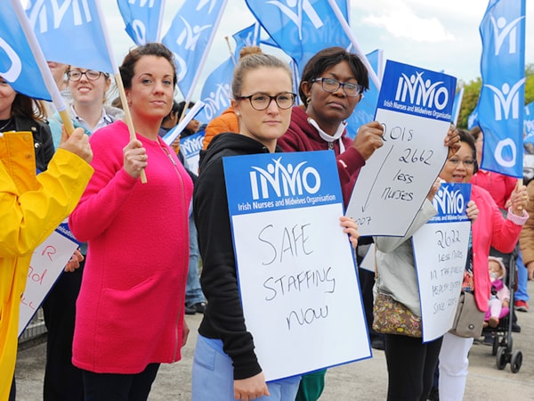Nurse standing with a better in a trade union logo in background